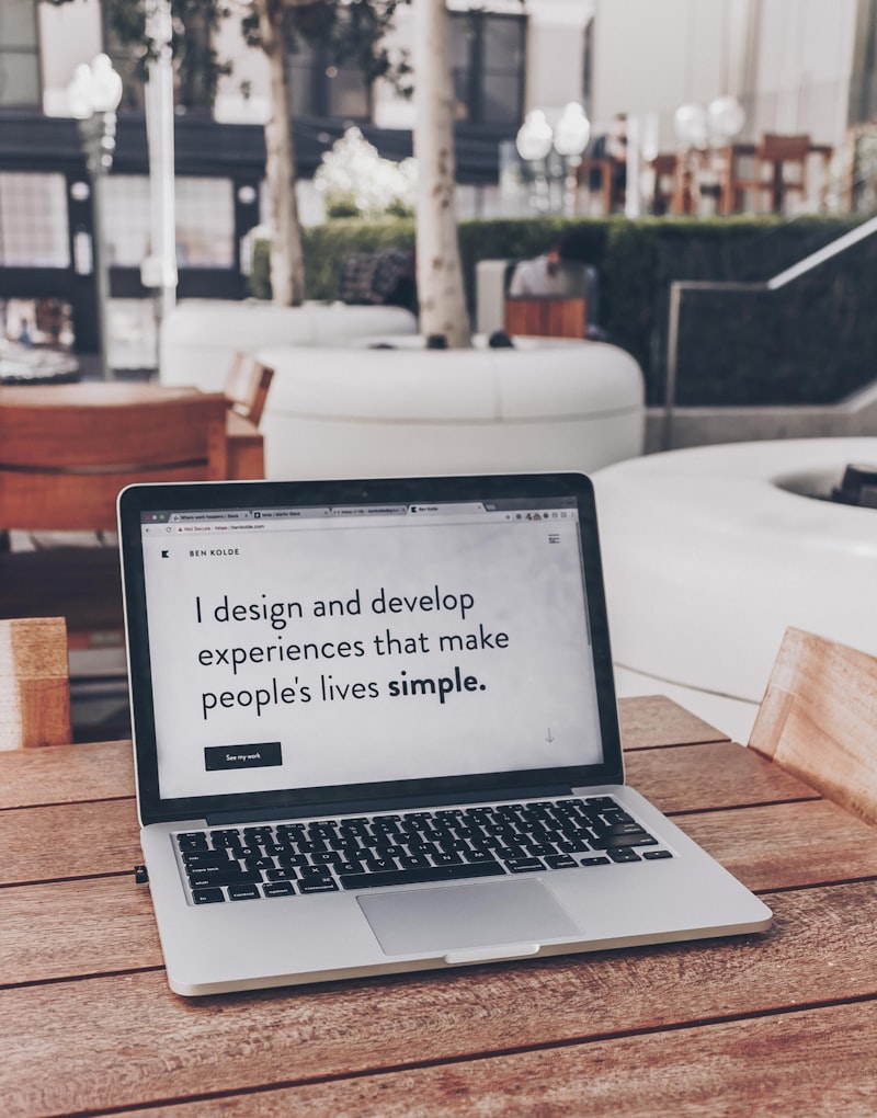 A laptop on an outdoor table showing a designer's portfolio site